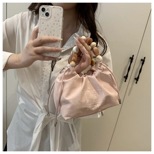 Detalle de bolso saco rosa con cordón y asa de cuentas marmoleadas de colores