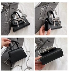 Vista detallada del mini bolso de cuero negro con lazo de cristal y correa de cadena