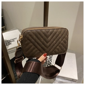 Detalle de bolso de cámara marrón oscuro con costuras en V y correa ancha de tela suave