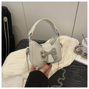 Detail einer weißen Handtasche aus Leder mit Silberschleife und edler Kette