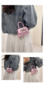 Vista detallada del mini bolso rosa con lazo de strass y cadena de plata para mujer