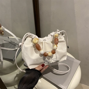Elegante bolso beige fruncido con asa de cuentas de ámbar y diseño minimalista