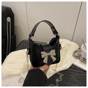 Detail des silbernen Schleifenverschlusses an einer schwarzen Mini-Handtasche
