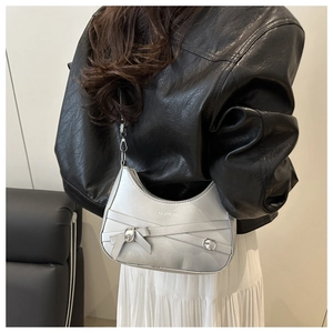 Détail du sac croissant argenté avec nœuds papillon, laçage et cuir au fini métallisé
