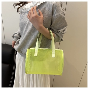 Fluorescent yellow mesh cosmetic bag with gold zipper held by a person in a casual outfit