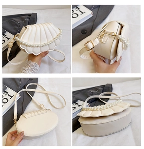 Detail of shell-shaped crossbody bag with pearl trim and faux leather texture