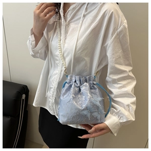Detail of light blue bucket bag with floral jacquard, 3D butterflies and pearl strap