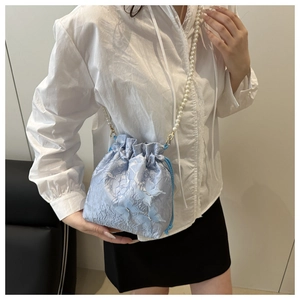 Détail du sac seau en jacquard bleu clair avec papillon 3D et bandoulière perles