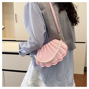 Detail view of pink shell-shaped bag with pearl chain strap and pleated faux leather texture