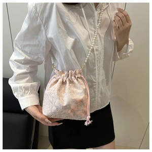 Detailed close-up of pink lace bucket bag featuring floral embroidery and pearl strap