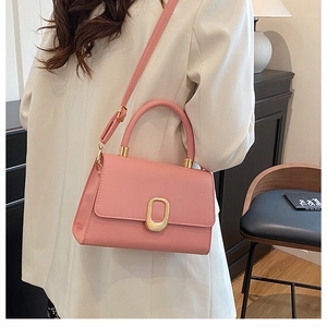 Detail of pink PU leather handbag with golden metal clasp shown in lifestyle setting