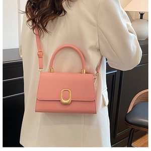 Pink leather handbag detail showing the gold oval buckle and top handle worn with a white blazer