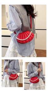 Detail of red shell-shaped crossbody bag with pearl chain and textured surface on model