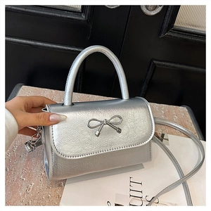 Detail of silver mini handbag with metallic bow clasp and sturdy top handle