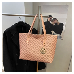 Detail of pink tote bag with M letter pattern, metal ring charm and top leather handles