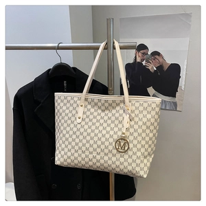 Detail of large tote bag with M-letter print and metallic charm for commute