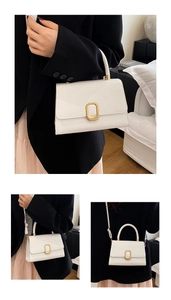 Detail of white glossy leather handbag with elegant gold oval clasp and top handle