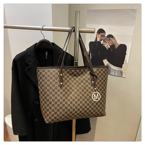 Detail of large tote bag with M-letter print, brown straps and round metal pendant