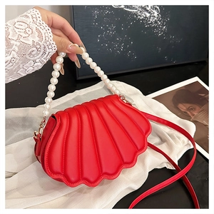 Detail of red shell crossbody bag with pearl handle and textured faux leather finish
