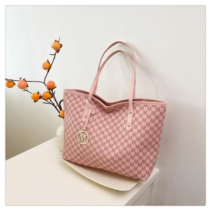 Detail of pink tote bag with repeating M-pattern and gold circular letter charm