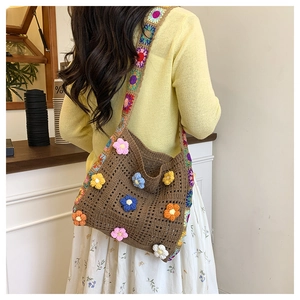 Detail of handmade crochet shoulder bag featuring colorful floral appliques and knit strap