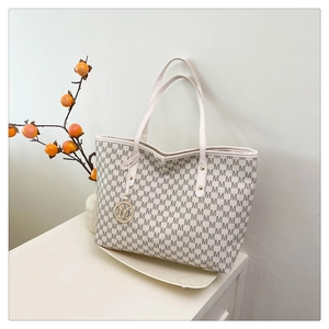 Detail of printed large tote bag with gold M-logo pendant and premium grain texture