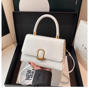 Close-up of cream leather handbag with gold oval metal clasp on a gift box background