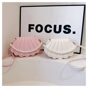 Close-up of pearl handles on stylish pink and white shell-shaped shoulder bags