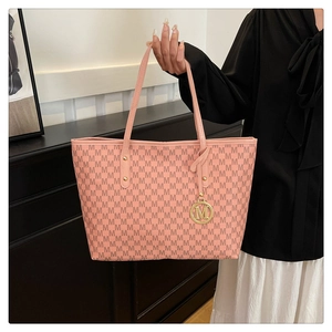 Detail of pink tote bag featuring all-over M-letter print and golden metal M-charm