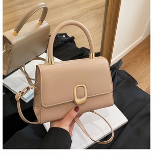 Close-up of beige leather handbag featuring a polished gold oval metal lock and handle