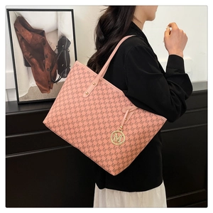 Side view of pink large capacity tote bag with M-pattern and gold charm on a shoulder