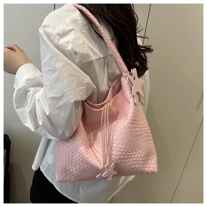 Detalle del bolso de hombro tejido rosa con colgante de estrella y textura elegante