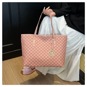 Close-up of pink tote bag with M-pattern print and a golden metal logo charm detail