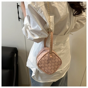 Détail du mini sac cylindre rose à monogramme avec chaîne dorée et poignée en cuir