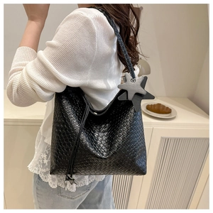 Detalle del bolso hobo de tejido negro con textura artesanal y colgante de estrella
