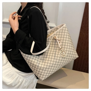 Detail view of large tote bag with M-letter monogram print and golden metal charm