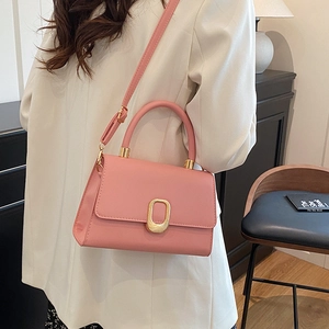 Pink matte faux leather handbag with gold oval clasp and adjustable strap shown on model
