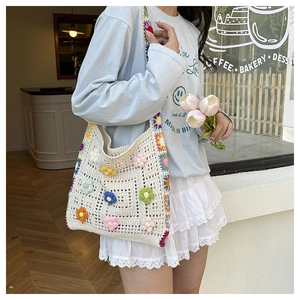 Detail der handgehäkelten Tragetasche mit bunten 3D-Blumen und Boho-Stil Webmuster