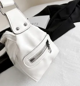 Detail shot of white faux leather bag showing rivet reinforced strap and side zipper pocket