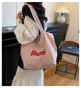 Pink canvas tote bag featuring red Beach text shown in a stylish home setting
