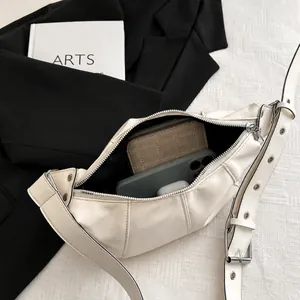 Detail view of the spacious creamy white crescent bag interior with silver zipper