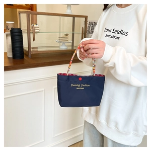 Dettaglio della borsa tote in nylon blu navy con manici intrecciati e ricami gialli