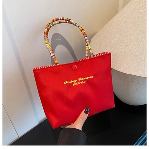 Détail du sac brodé rouge avec poignées rayées et doublure à carreaux rouges