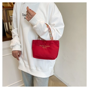 Dettaglio borsa in tela rossa con manici in perline colorate e logo dorato