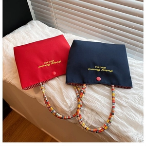Détail de mini sacs rouge et bleu avec poignées tressées colorées et bouton-pression