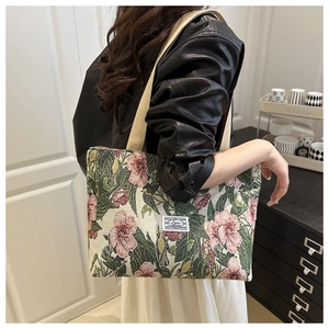 Detail of vintage floral jacquard tote bag with white woven logo and thick canvas straps