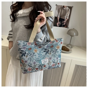 Close-up of vintage blue floral jacquard tote bag with logo label and canvas handles