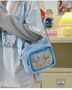 Detail of light blue cat-ear ita bag with transparent window and four rabbit badges