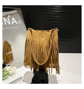 Détail du sac à bandoulière en daim marron montrant les franges boho et la texture