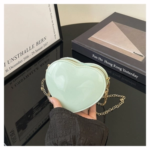 Detail einer hellgrünen herzförmigen Gelée-Tasche mit Glanzfinish und goldener Kette